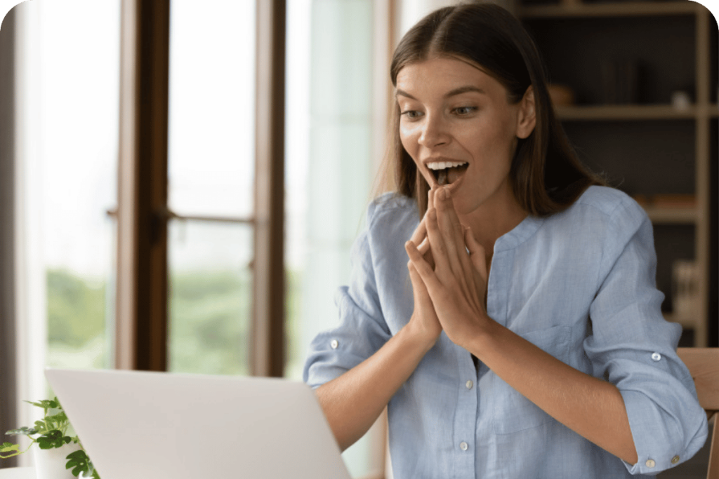 Woman reacting with excitement while looking at her laptop.