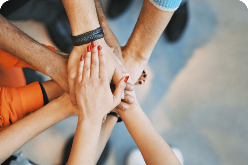 Team members stacking their hands together in a show of unity and collaboration.