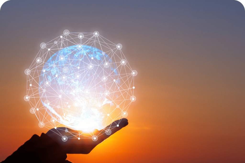 A hand holding a glowing digital globe with connected network points at sunset.
