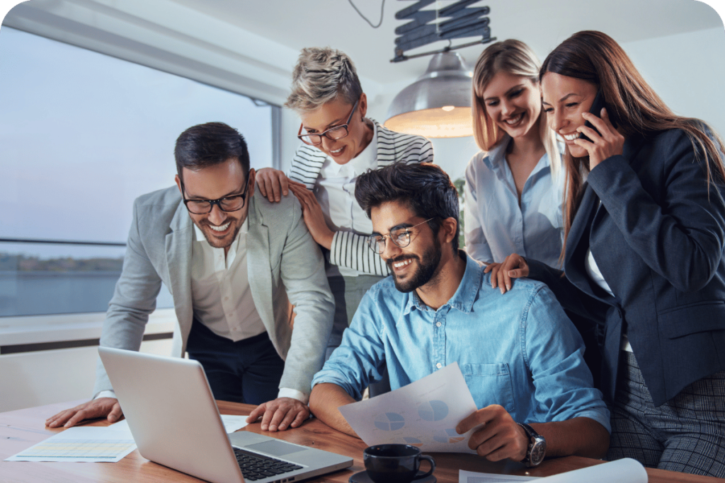 Team reviewing results together around a laptop and celebrating the progress.